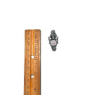 Small silver dangel labyrinth pendant next to a wooden ruler on a white background