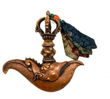 A bronze-colored metal kartika with a decorative handle and a small piece of cloth attached to it.