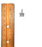 Small silver pendant next to a wooden ruler on a white background