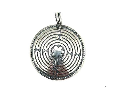 Silver pendant with intricate labrynth design on a white background