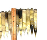 Set of elongated, teardrop-shaped ocrystals with a ruler for scale on a white background